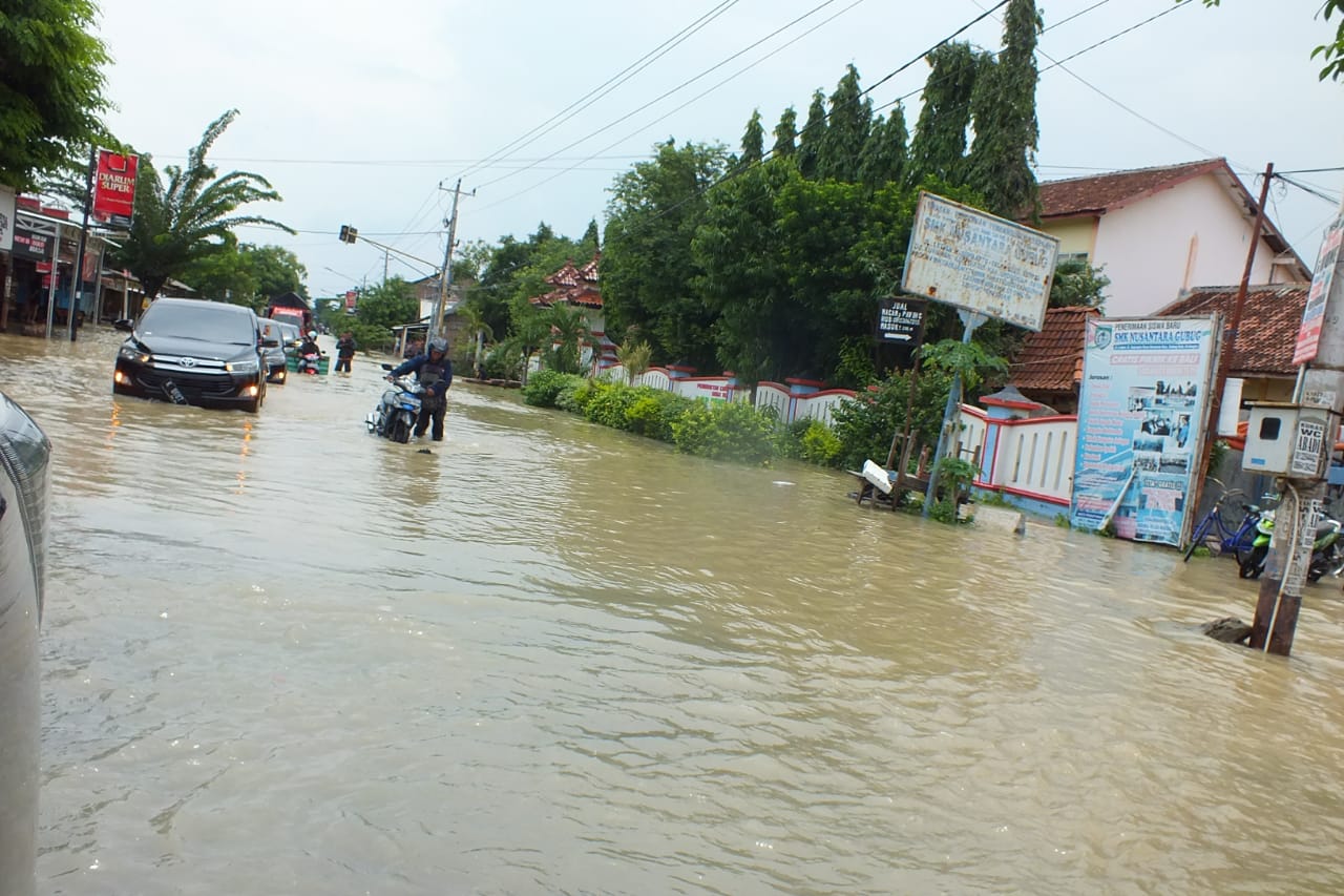 Seorang warga mendorong kendaraannya menerjang banjir