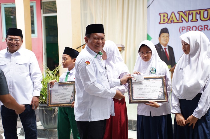 Wakil Ketua Komisi VIII DPR RI KH Abdul Wachid didampingi Kepala Kemenag Demak menyerahkan bantuan PIP secara simbolis kepada siswa madrasah di MI Miftahul Huda Bonangrejo