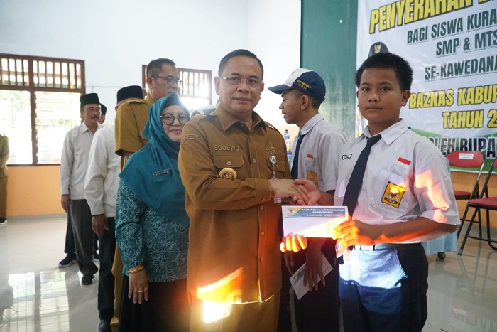 Bupati Pati Sudewo menyerahkan bantuan Baznas secara simbolis kepada siswa SMP di Balai Desa Kutoharjo.