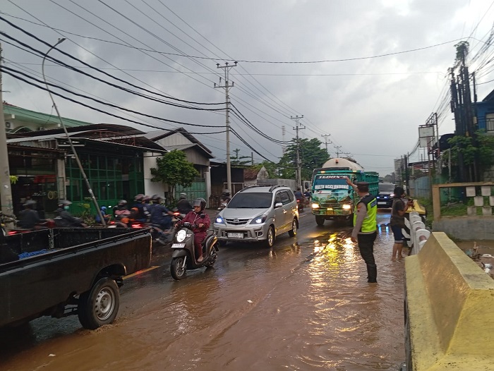 Petugas Satlantas Polres Kudus mengatur arus kendaraan di Jalan Raya Kudus–Pati, Desa Hadipolo, Jekulo, Kudus, Jumat (26/12/2025) sore
