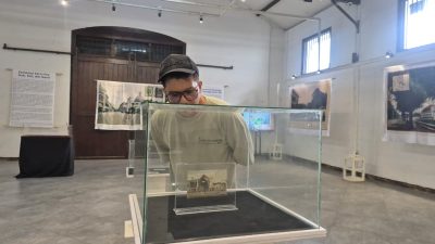 Seorang pengunjung sedang mengamati pameran kartu pos di Gedung Oudetrap