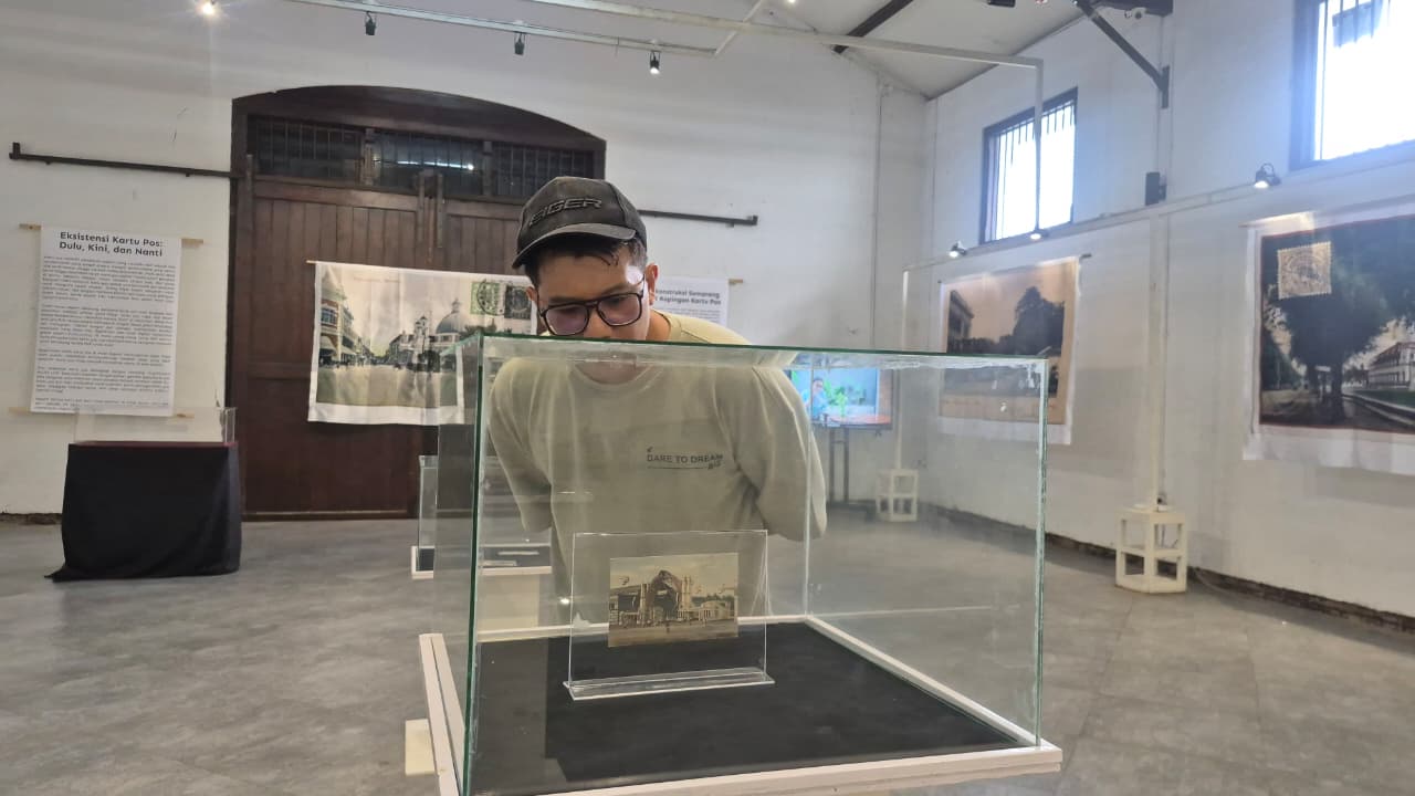 Seorang pengunjung sedang mengamati pameran kartu pos di Gedung Oudetrap