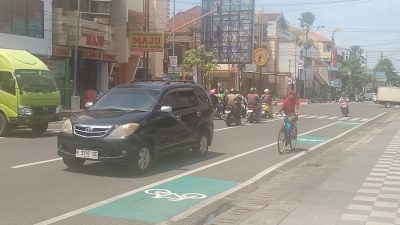 Ibu-ibu tengah melintas di lajur sepeda pada siang hari