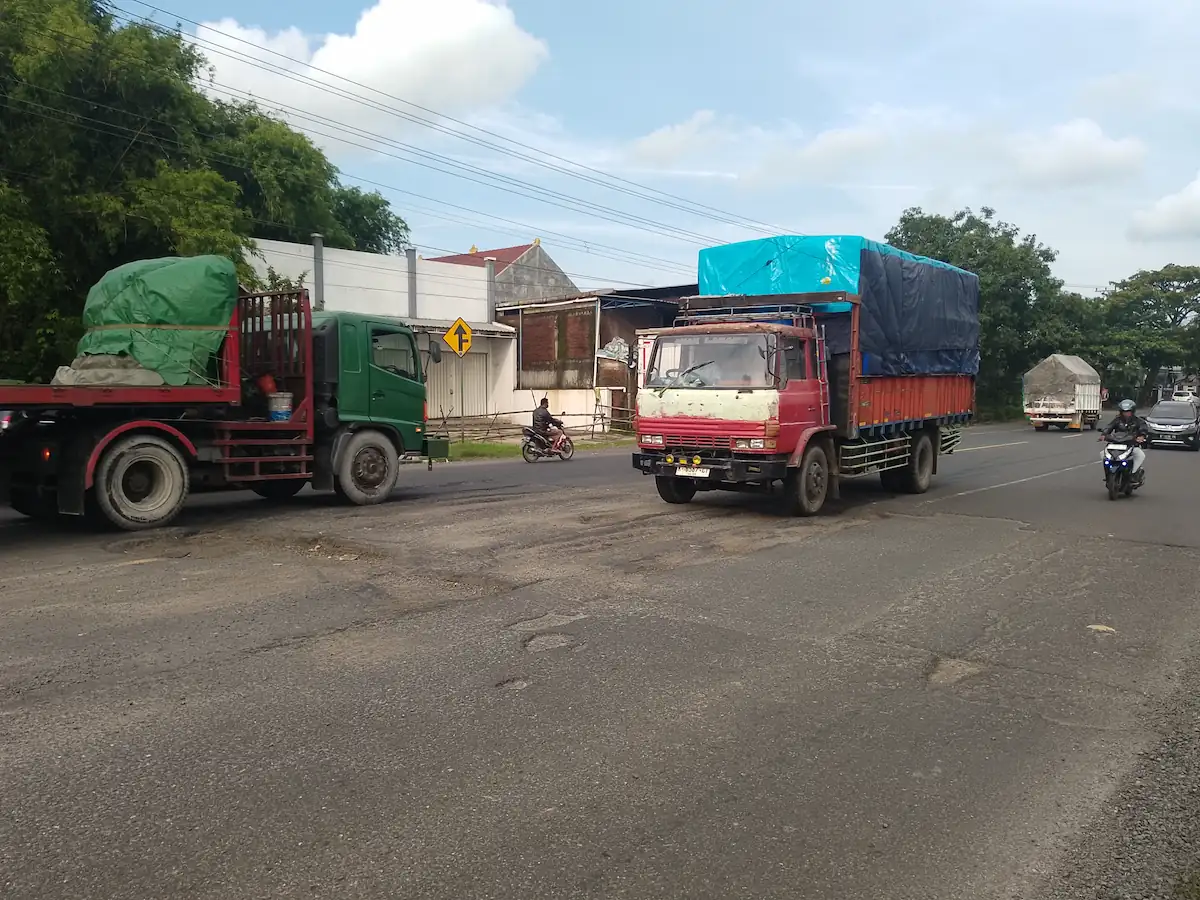 Kondisi jalan berlubang di jalur Kudus-Pati Desa Gondoharum yang membahayakan pengendara.