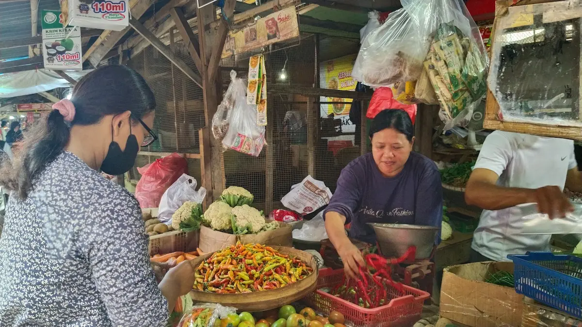 Suasana aktivitas tawar-menawar antara pedagang dan pembeli di lapak sayur Pasar Puri Pati di tengah lonjakan harga sembako pada awal bulan Ramadan.