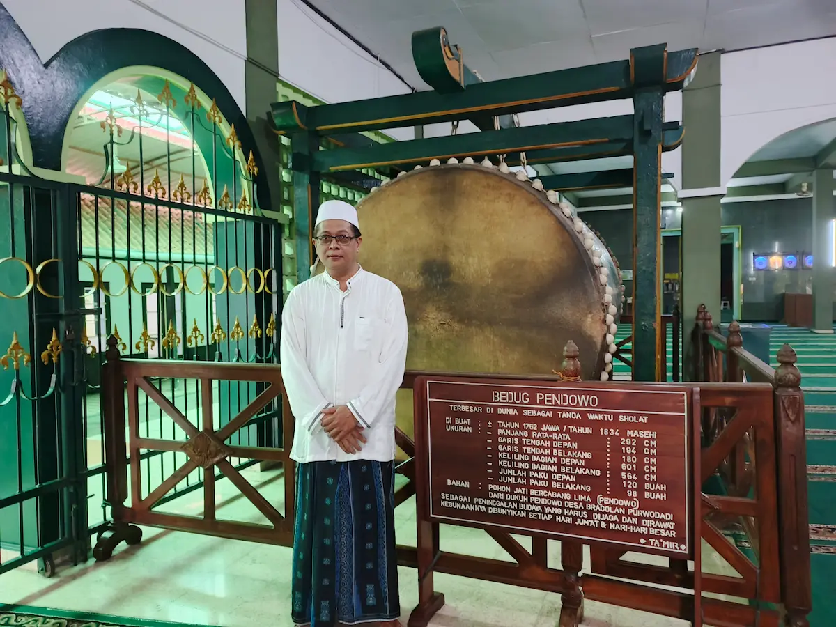 Ketua Takmir Masjid Agung Purworejo, KH Najib Sahfrudin, berdiri di serambi masjid menunjukkan kemegahan Bedug Pendowo Purworejo yang merupakan salah satu bedug terbesar di dunia.