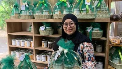Etik Yuniarti sedang merangkai bingkisan kue kering (hampers) Lebaran menggunakan wadah anyaman rotan yang estetik di rumah produksinya.