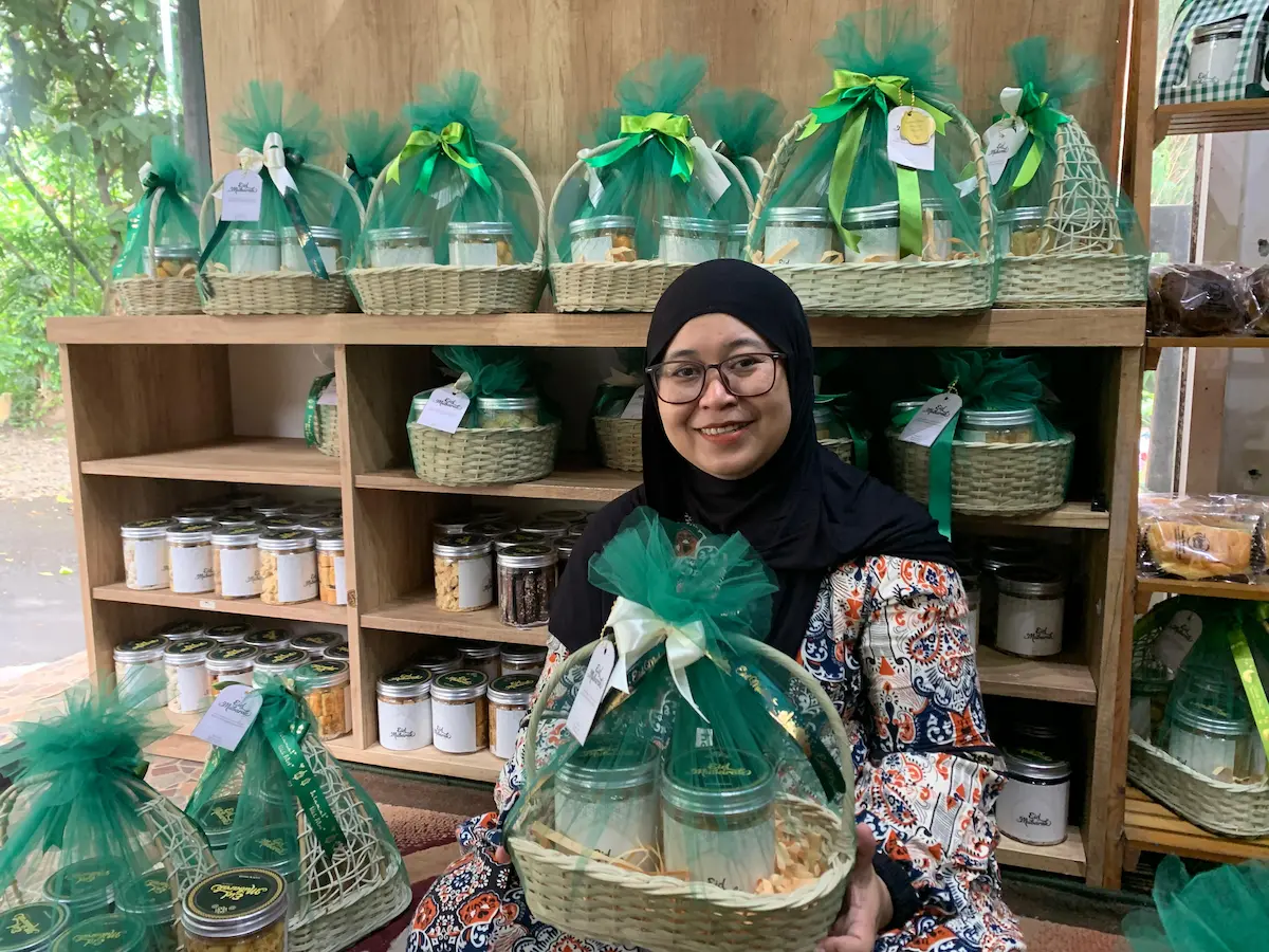 Etik Yuniarti sedang merangkai bingkisan kue kering (hampers) Lebaran menggunakan wadah anyaman rotan yang estetik di rumah produksinya.