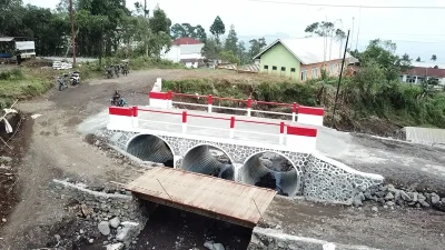 Seorang warga berjalan melintasi jembatan baja baru di Desa Penakir Pemalang usai jembatan lama hancur akibat banjir.