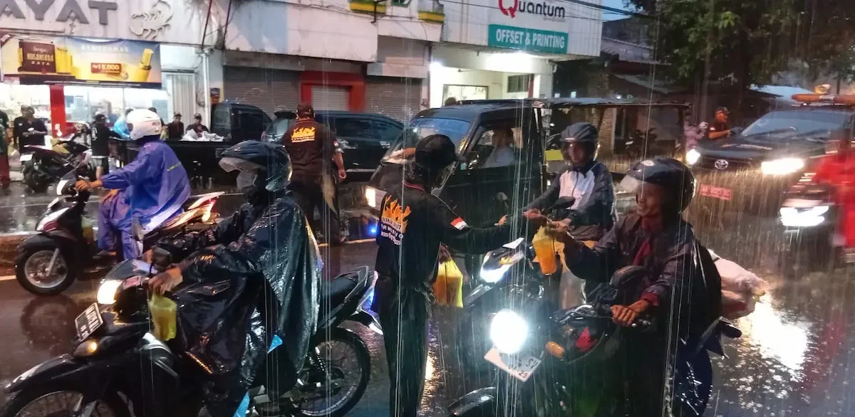 Sejumlah anggota ormas Laskar Langit Purworejo membagikan paket takjil di tengah guyuran hujan kepada tukang becak di persimpangan jalan.