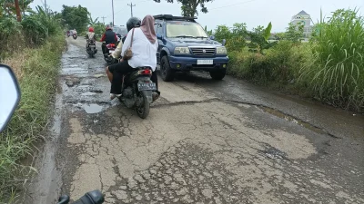 Kendaraan melintas di jalan berlubang dan rusak parah yang berada di salah satu ruas jalan di wilayah Kabupaten Pati.