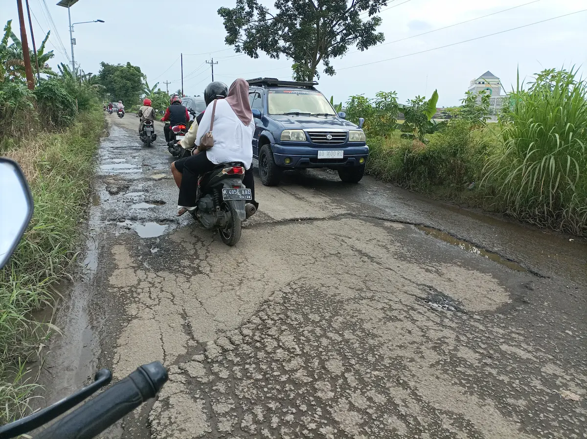 Kendaraan melintas di jalan berlubang dan rusak parah yang berada di salah satu ruas jalan di wilayah Kabupaten Pati.