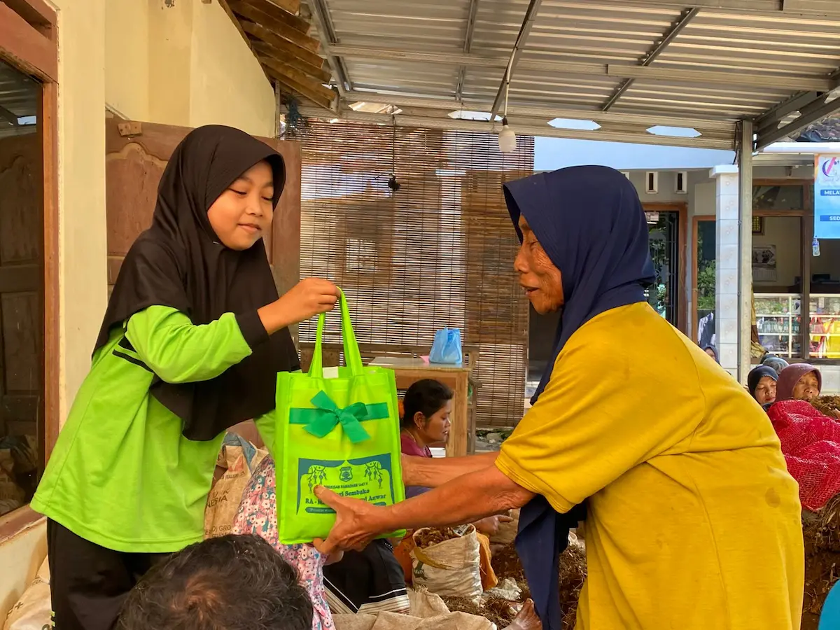 Siswa-siswi Madrasah Darul Anwar Kudus membagikan paket sembako secara langsung kepada masyarakat kurang mampu di Desa Cranggang.