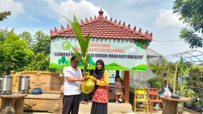 Kepala Desa Ngembalrejo Zakaria sedang menanam bibit pohon kelapa sebagai simbol peresmian program pelestarian lingkungan GEMBIRA di Kabupaten Kudus.