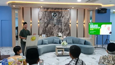 Direktur RSI Sunan Kudus Ahmad Syarifudin berdiri memberikan presentasi tentang inovasi layanan Materna untuk ibu hamil di depan layar proyektor.