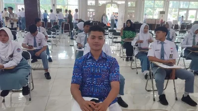 Seorang siswa berseragam rapi sedang fokus menatap layar laptop saat mengerjakan tes CAT seleksi Paskibraka.