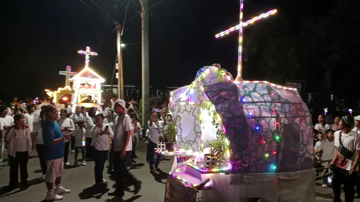 Ribuan jemaat gereja berjalan beriringan membawa obor dan lilin menyusuri jalan desa pada malam hari yang gelap.
